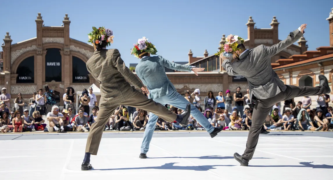 Three dancers perform with their backs turned