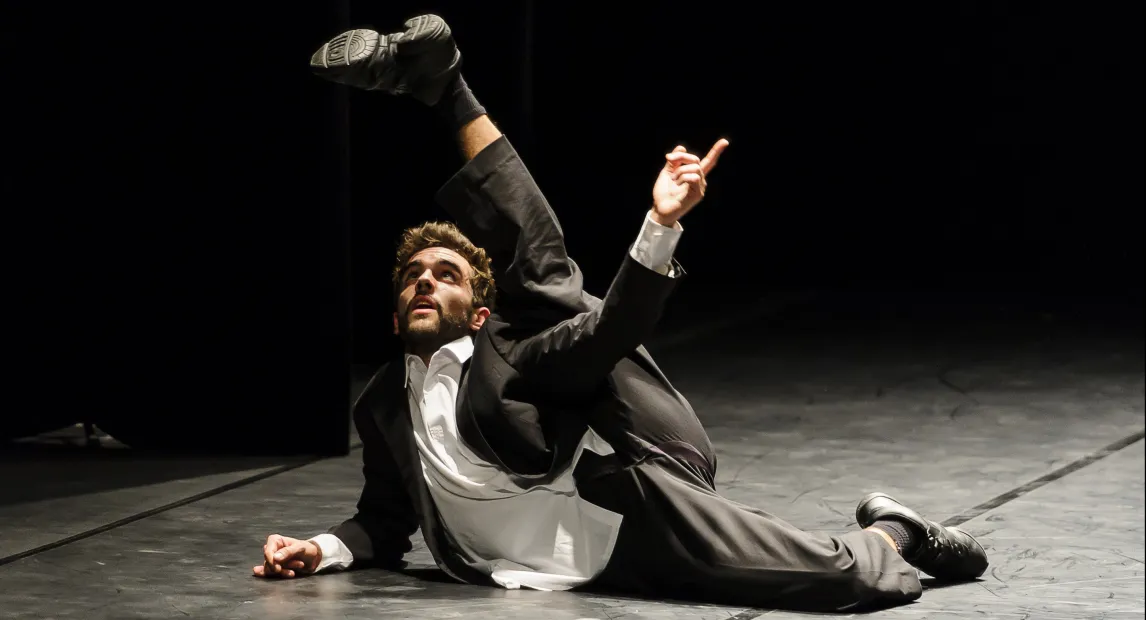 Un bailarín danza, tiene la pierna alzada.