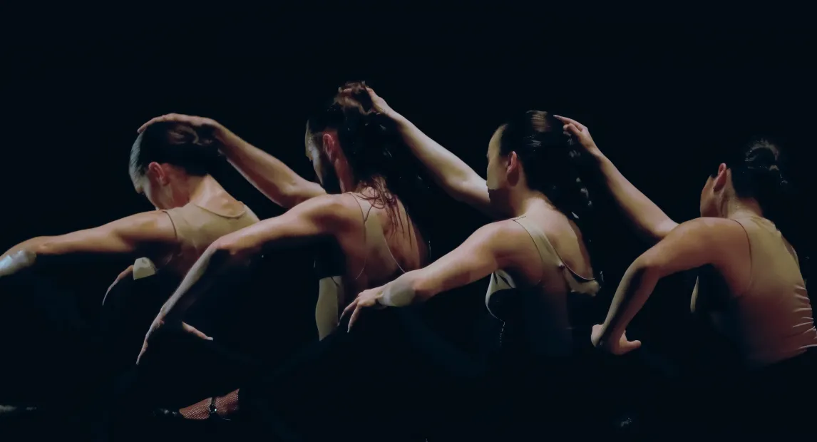 Un grupo de mujeres bailan mientras se tocan las cabezas.