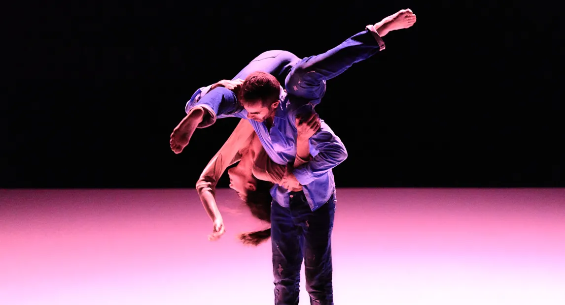 Dos bailarines danzan. Un hombre sostiene a una chica en sus hombros.