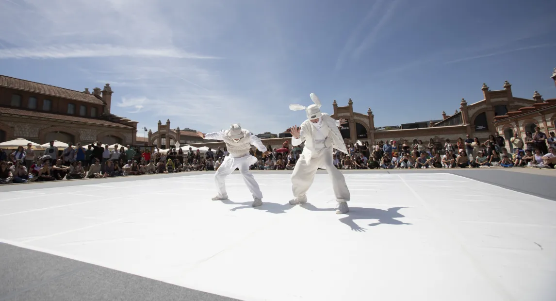 Two dancers dressed in white perform a dance