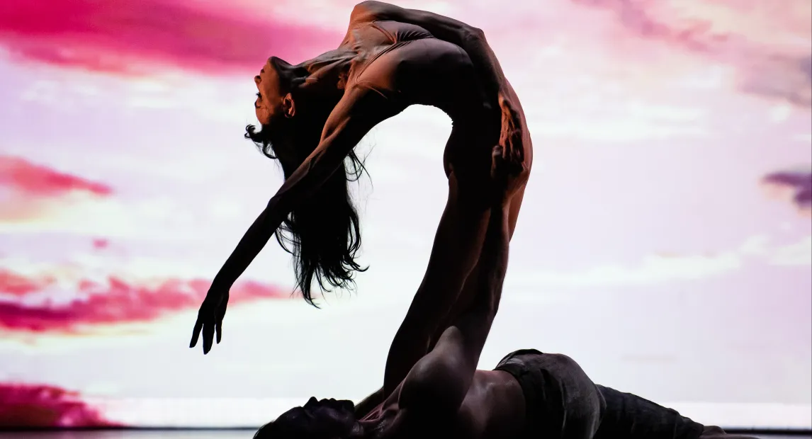 Una bailarina danza, en el fondo hay un atardecer recreado por luces.