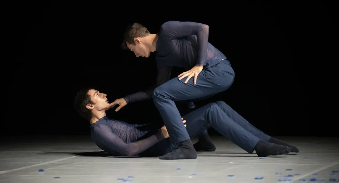Dos bailarines danzan, uno de ellos está sobre el piso.