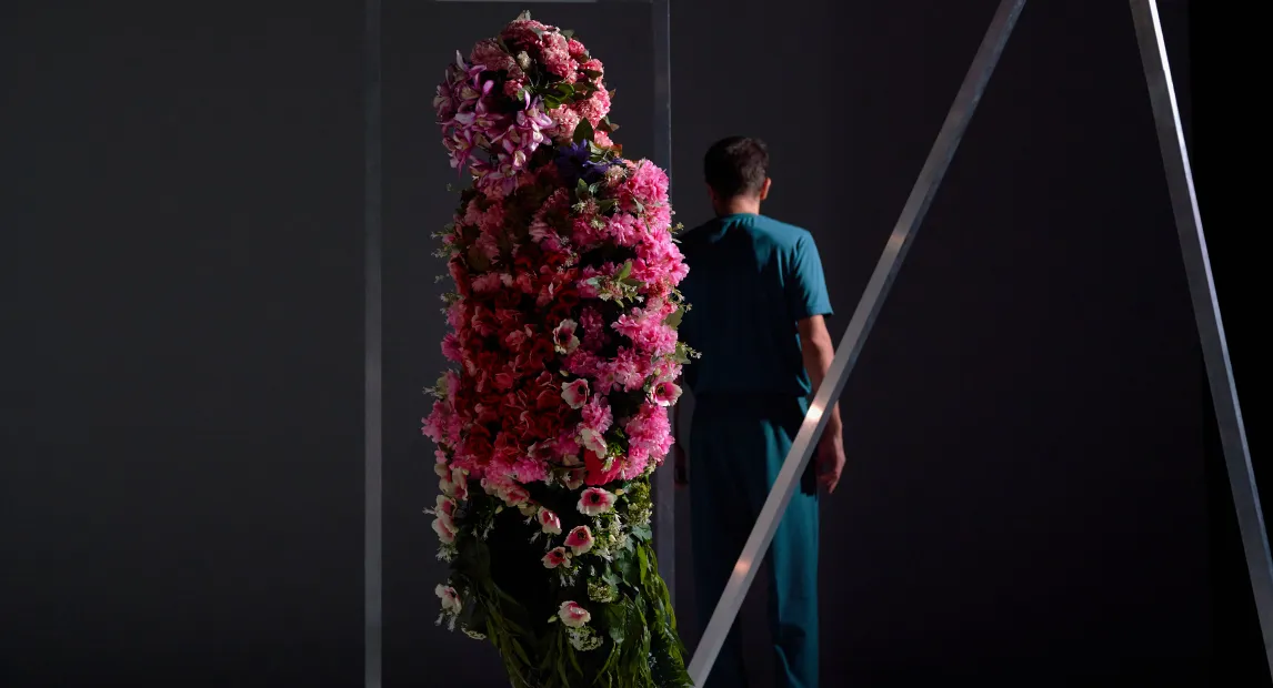 Un bailarín lleno de flores, de espalda esta otro bailarín.