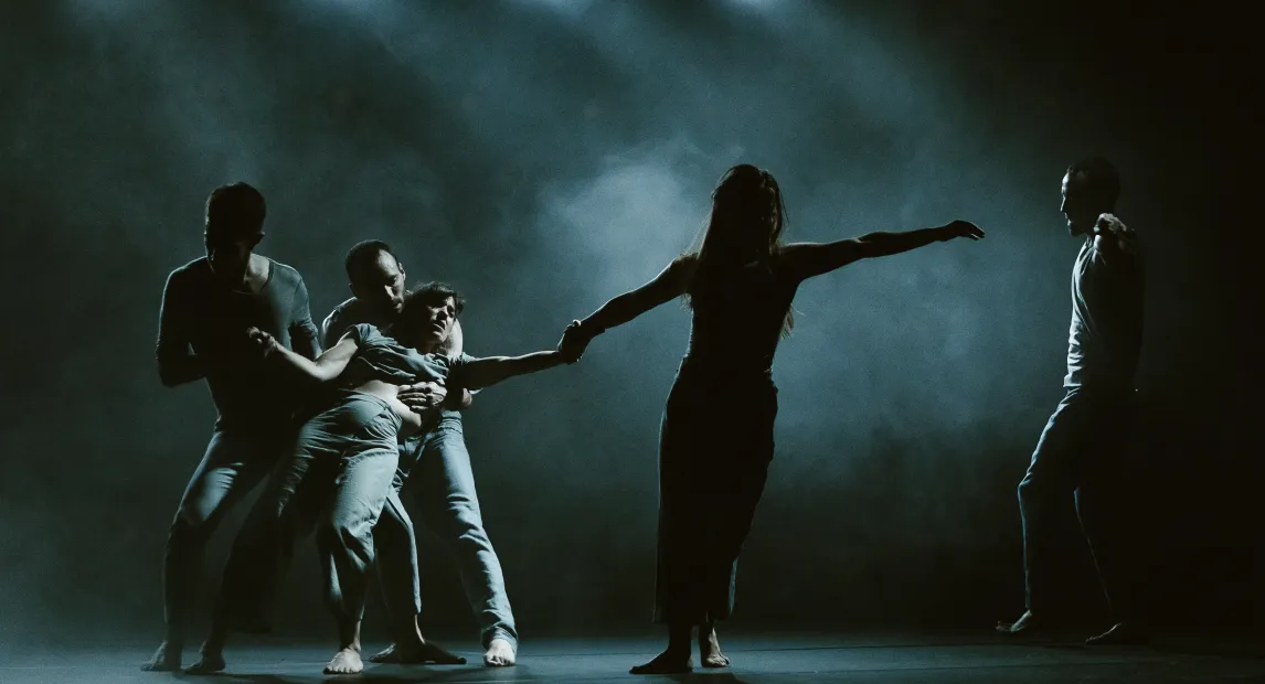 Cinco bailarines  danzan en medio del humo