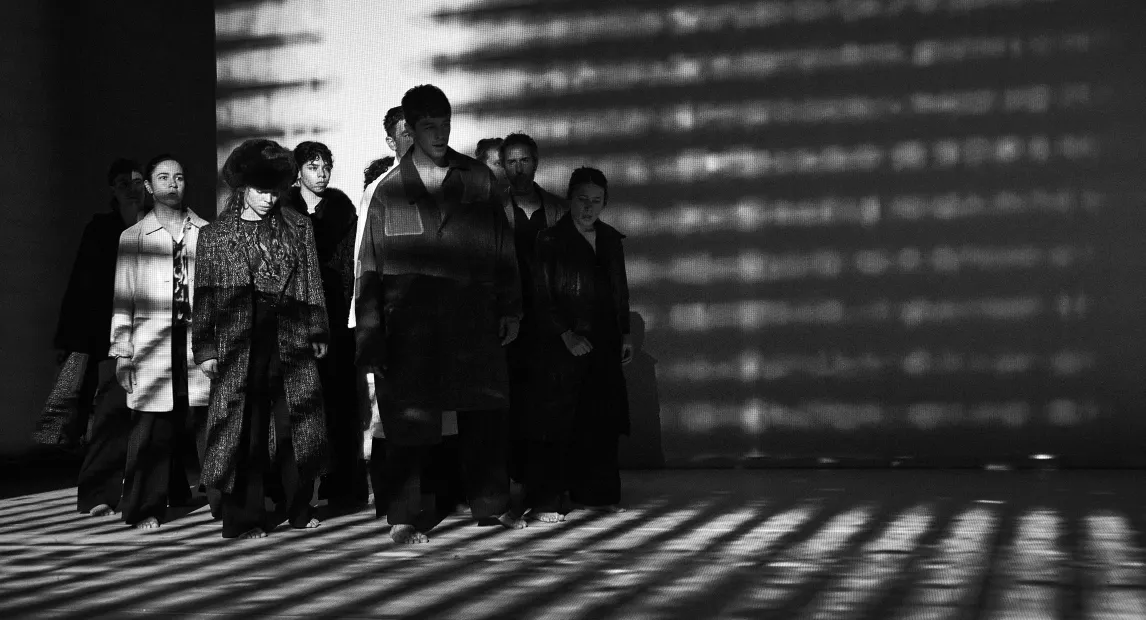 Grupo de personas vestidas con abrigos iluminados a contra luz