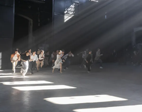 Un grupo de bailarines corren. Rayos de luz entran por las ventanas.