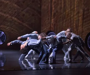 Laurent Philippe Un grupo de bailarines son iluminados por una luz desde arriba.