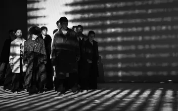 Grupo de personas vestidas con abrigos iluminados a contra luz